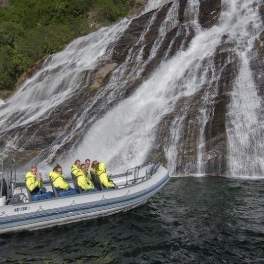 a person riding on the back of a boat next to a waterfall